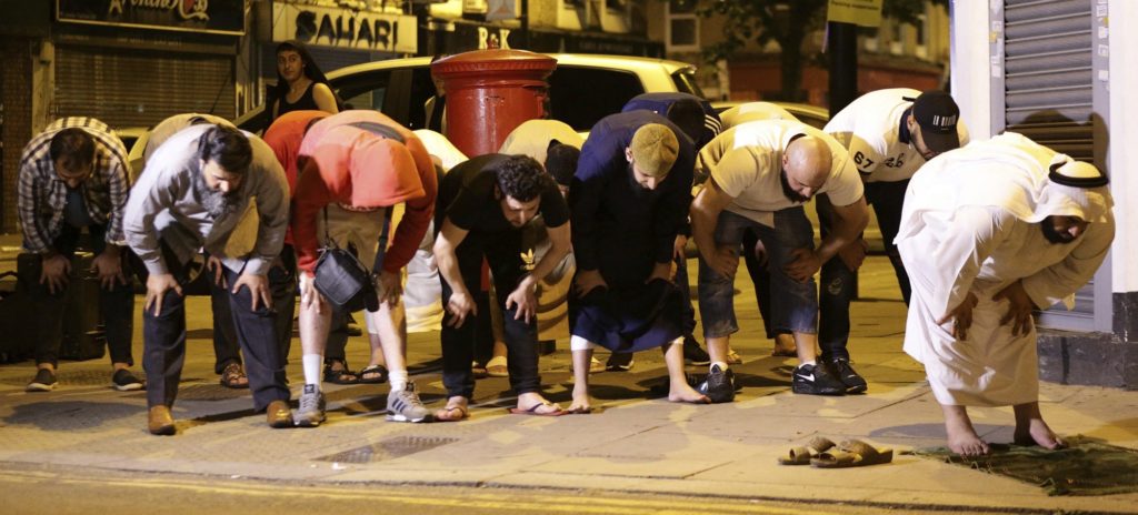 Local people observe prayers at Finsbury Park where a vehicle struck pedestrians in London Monday, June 19, 2017. Police say a vehicle struck pedestrians near a mosque in north London, leaving several casualties and one person was arrested. (Yui Mok/PA via AP)