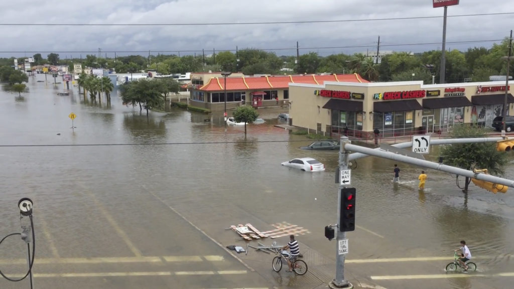 This image made from a video shows a view from U.S. Route 59 of flooding on West Bellfort Avenue in Houston, Sunday, Aug. 27, 2017. The remnants of Hurricane Harvey sent devastating floods pouring into Houston Sunday as rising water chased thousands of people to rooftops or higher ground. (DroneBase via AP)