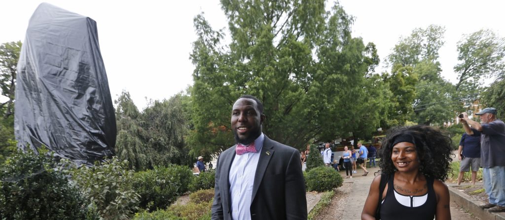 Charlottesville city council member Wes Bellamy, left, walks with resident Aaliyah Jones, right past the covered statue of Confederate General Robert E. Lee in Emancipation park in Charlottesville, Va., Wednesday, Aug. 23, 2017. The move to cover the statues is intended to symbolize the city's mourning for Heather Heyer, killed while protesting a white nationalist rally earlier this month. (AP Photo/Steve Helber)