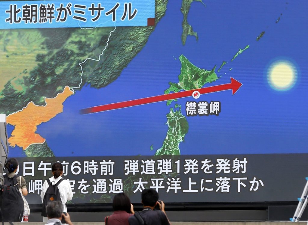 People walk by a TV news program reporting North Korea's missile launch, in Tokyo, Tuesday, Aug. 29, 2017. North Korea fired a ballistic missile from its capital Pyongyang that flew over Japan before plunging into the northern Pacific Ocean, officials said Tuesday, an aggressive test-flight over the territory of a close U.S. ally that sends a clear message of defiance as Washington and Seoul conduct war games nearby. (AP Photo/Shizuo Kambayashi)