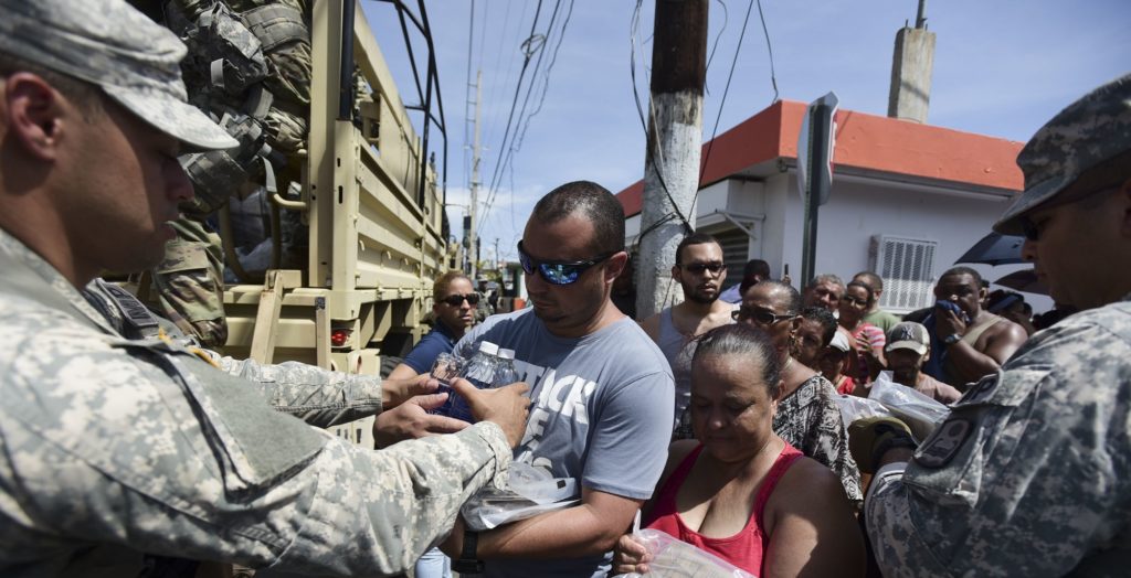 National Guardsmen arrive at Barrio Obrero in Santurce to distribute water and food among those affected by the passage of Hurricane Maria, in San Juan, Puerto Rico, Sunday, Sept. 24, 2017. Federal aid is racing to stem a growing humanitarian crisis in towns left without fresh water, fuel, electricity or phone service by the hurricane. (AP Photo/Carlos Giusti)