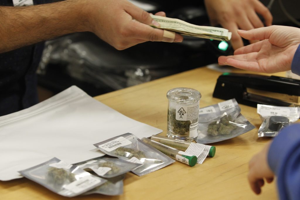 A customer purchases marijuana at Harborside marijuana dispensary, Monday, Jan. 1, 2018, in Oakland, Calif. Starting New Year's Day, recreational marijuana can be sold legally in California. (AP Photo/Mathew Sumner)