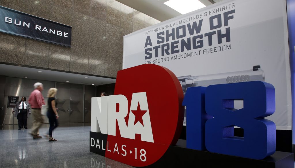 People walk by NRA convention signage in the Kay Bailey Hutchison Convention Center in Dallas, Thursday, May 3, 2018. The convention is scheduled to go through Sunday. (AP Photo/Sue Ogrocki)