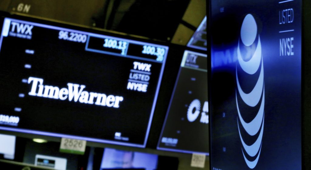 The logos for Time Warner and AT&T appear above alternate trading posts on the floor of the New York Stock Exchange, Wednesday, June 13, 2018. A federal judge has approved the $85 billion mega-merger of AT&T and Time Warner, potentially ushering in a wave of media consolidation while shaping how much consumers pay for streaming TV and movies. (AP Photo/Richard Drew)