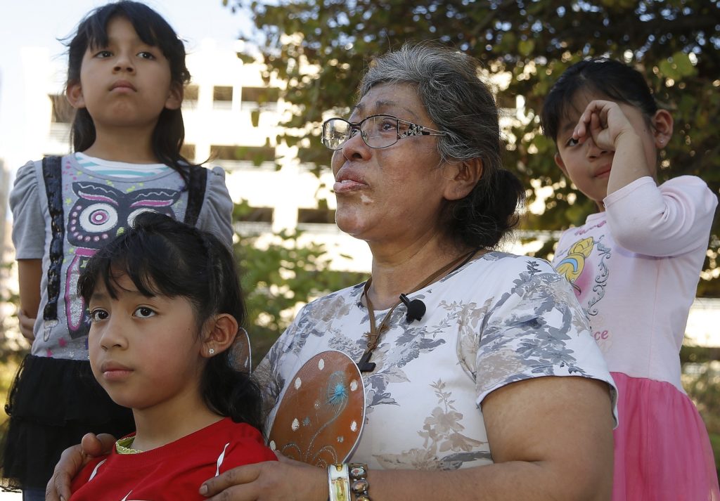 Lucia Ajas, middle, talks about her and her children, Regina Vargas, 7, left, Akemi Vargas, 8, second from left, and Trinidad Vargas, 5, right, being separated from their father during an immigration family separation protest in front of the Sandra Day O'Connor U.S. District Court building, Monday, June 18, 2018, in Phoenix. An unapologetic President Donald Trump defended his administration's border-protection policies Monday in the face of rising national outrage over the forced separation of migrant children from their parents. (AP Photo/Ross D. Franklin)
