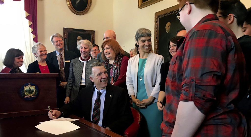 Gov. Phil Scott, seated, smiles after signing a bill requiring that all single occupancy restrooms in Vermont public buildings be marked as gender neutral, Friday, May 11, 2018 in Montpelier, Vt., The new law takes effect July 1. (AP Photo/David Jordan)