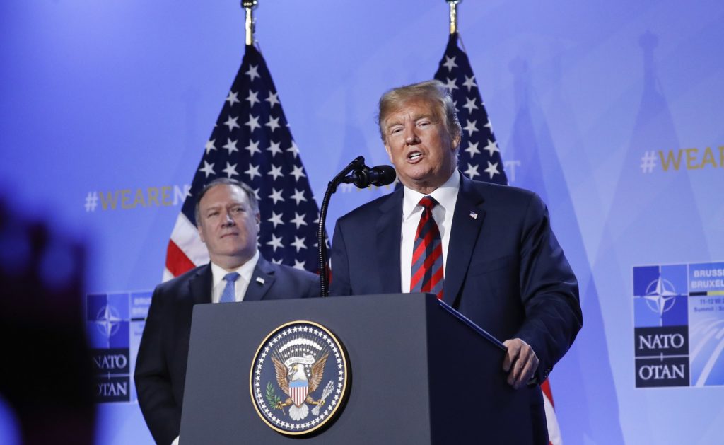 The silhouette of a journalist's hand is seen in the foreground as U.S. President Donald Trump speaks during a news conference before departing the NATO Summit in Brussels, Belgium, Thursday, July 12, 2018. With Trump on stage is Secretary of State Mike Pompeo, left. (AP Photo/Pablo Martinez Monsivais)