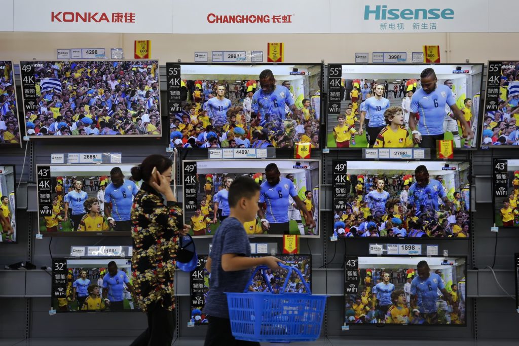 A woman and a child pass Chinese brands of flat screen TVs on display at a hypermarket in Beijing, Wednesday, July 11, 2018. China's government has criticized the latest U.S. threat of a tariff hike as "totally unacceptable" and vowed to retaliate in their escalating trade war. The Commerce Ministry on Wednesday gave no details, but Beijing responded to last week's U.S. tariff hike on $34 billion of imports from China by increasing its own duties on the same amount of American goods. (AP Photo/Andy Wong)