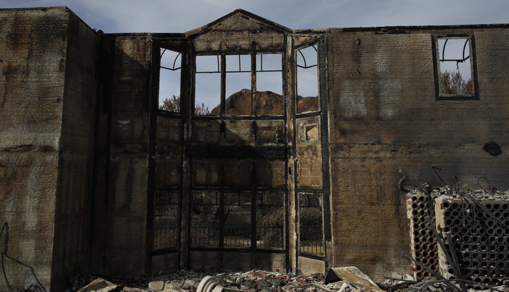 A mountain is seen through charred window frames of a mansion burned down by the Woolsey Fire Tuesday, Nov. 13, 2018, in Agoura Hills, Calif. (AP Photo/Jae C. Hong)