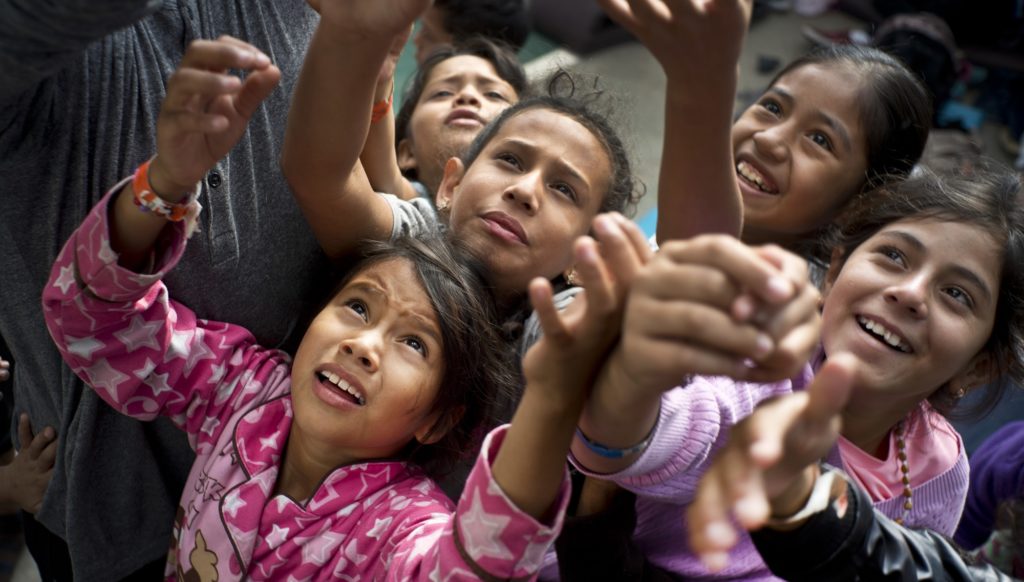 Migrants children, who are part of the Central American caravan, vie for candy tossed out to them by a social worker at a shelter in Tijuana, Tuesday, Nov. 20, 2018. U.S. border inspectors are processing only about 100 asylum claims a day at Tijuana's main crossing to San Diego, and there was already a waiting list of 3,000 when the new migrants arrived, so most will have to wait months to even be considered for asylum. (AP Photo/Ramon Espinosa)