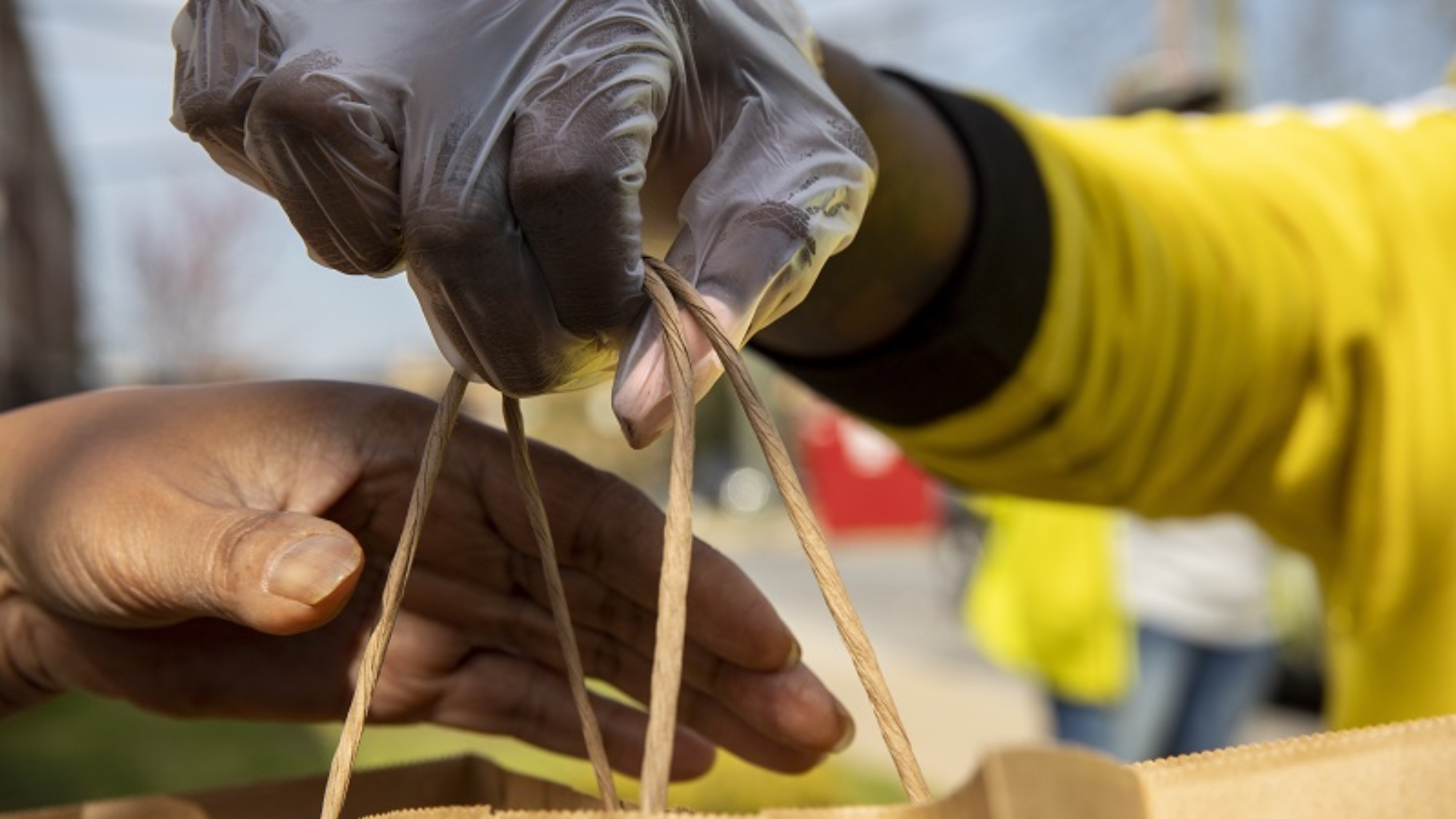 In this March 29, 2020, photo, Regina Summers hands out hot meals donated by Clydes Restaurant Group and distributed by volunteers coordinating with Martha's Table in southeast Washington. Neighborhood deliveries are part of a new Martha's Table initiative, along with community partners, to get needed food directly to the neighborhoods they serve. These volunteers are the tip of the spear for a grassroots community effort to keep Washington's most vulnerable neighborhoods fed during the unprecedented coronavirus crisis which has nearly shut down the American economy. (AP Photo/Jacquelyn Martin)