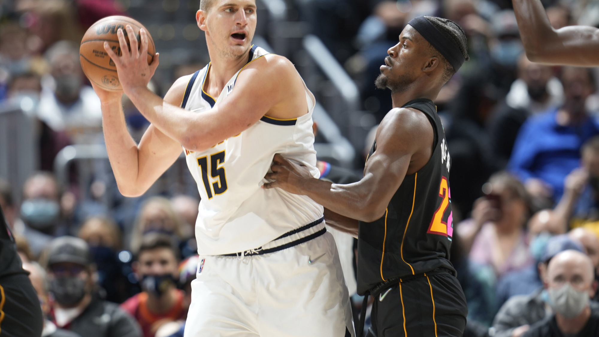 Denver Nuggets center Nikola Jokic, left, looks to pass the ball as Miami Heat forward Jimmy Butler defends in the first half of an NBA basketball game Monday, Nov. 8, 2021, in Denver. (AP Photo/David Zalubowski)