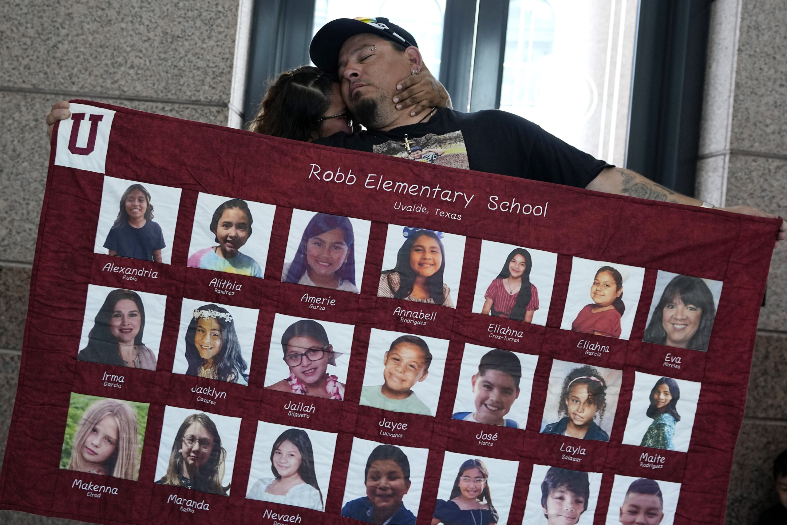 Abel Lopez, right, father of Xavier Lopez who was killed in the shootings in Uvalde, Texas, holds a banner honoring the victims