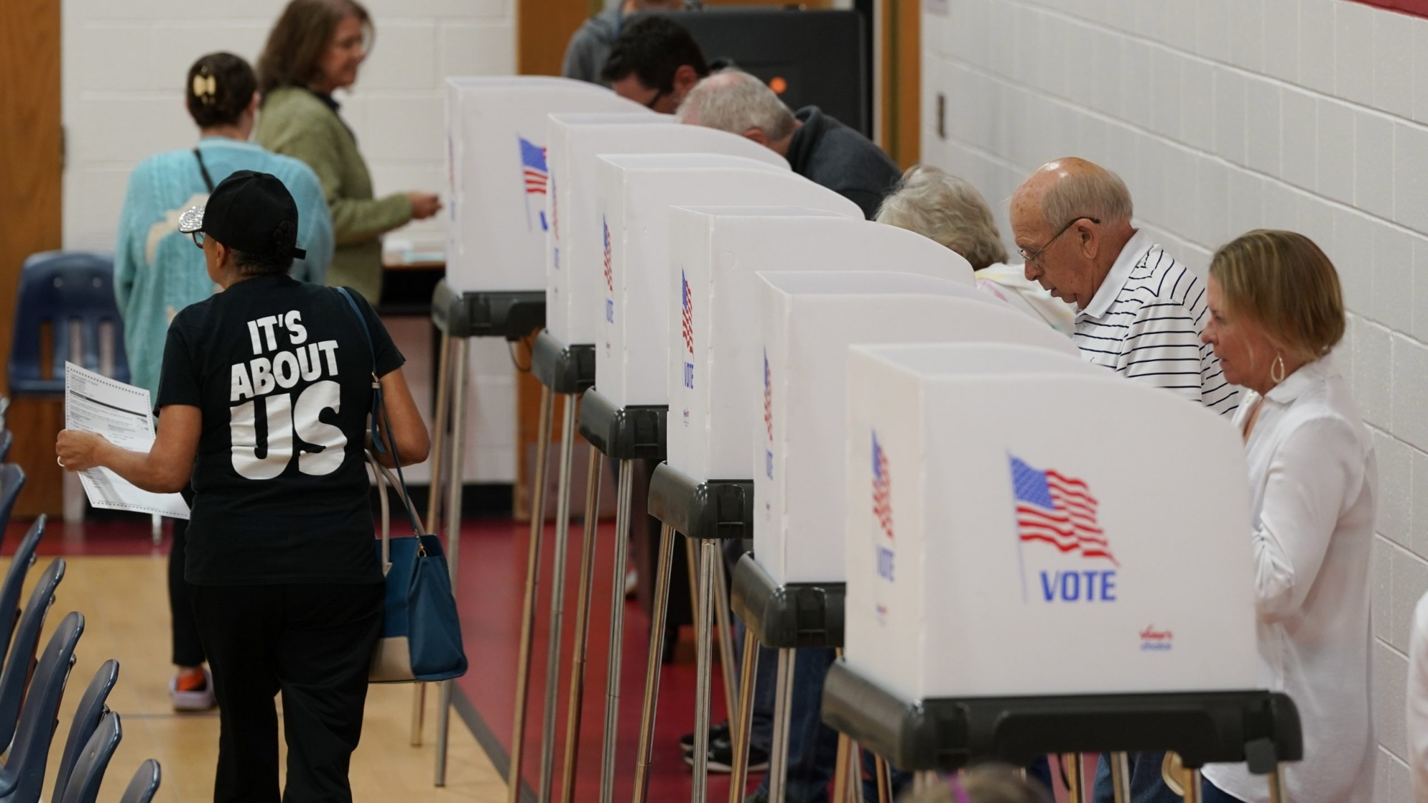 A voter, left, carries her ballot to the counting machine after voting at a polling station Tuesday Nov. 7, 2023, in Richmond, Va. (AP Photo/Steve Helber)